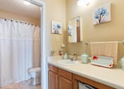 Thumbnail 12 of 16 - a bathroom with a sink and a toilet and a shower in a Village Square Apartment Home