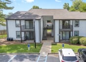 Thumbnail 15 of 28 - a white apartment building with cars parked in front of it