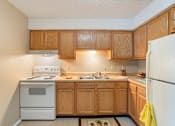 Thumbnail 8 of 16 - a kitchen apartment at Village Square with white appliances and wooden cabinets