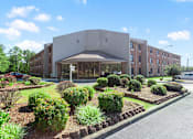 Thumbnail 1 of 16 - The professionally landscaped entrance to Village Square senior apartments in Russellville, AL