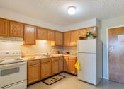 Thumbnail 7 of 16 - Village Square Apartment kitchen with white appliances and wooden cabinets