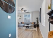 Thumbnail 25 of 48 - looking from a hallway into a large living room with large windows, an illuminated fan, and model furnishings