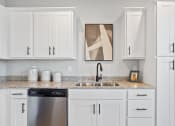 Thumbnail 29 of 48 - a kitchen with white cabinets, granite countertops, a stainless steel dishwasher and sink