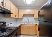 Thumbnail 6 of 14 - a kitchen with black appliances, wood cabinets, and granite countertops in a home at Mountainside Apartments