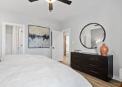 Thumbnail 38 of 48 - a spacious bedroom with an illuminated ceiling fan, model furnishings, and wood-style flooring