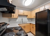 Thumbnail 5 of 14 - A Mountainside Apartments kitchen with black appliances and wood cabinets