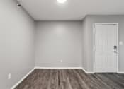 Thumbnail 25 of 28 - an empty living room with a white door and wood flooring