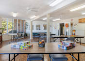 Thumbnail 4 of 16 - a large community room with tables, chairs, puzzles, and large windows at Village Square