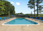Thumbnail 14 of 28 - a swimming pool with blue chairs around it and trees