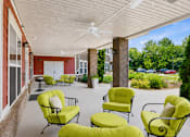 Thumbnail 6 of 15 - A patio with yellow chairs and a ceiling fan.