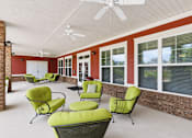 Thumbnail 3 of 15 - A patio with green chairs and a ceiling fan.