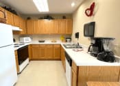 Thumbnail 12 of 24 - a kitchen at Algonquin Manor with white appliances and wood cabinetry