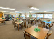 Thumbnail 7 of 24 - a large community room with many tables and chairs and a vending machine at Algonquin Manor