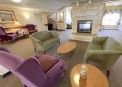 Thumbnail 4 of 24 - a cozy lobby with a fireplace and several easy chairs with nearby tables at Algonquin Manor