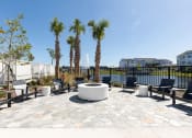 Thumbnail 16 of 48 - firepit with lounge chairs surrounded by trees and the pond at Lake Nona Concorde