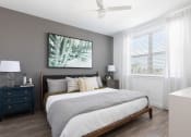Thumbnail 38 of 48 - a bedroom with a ceiling fan, large window, wood-style floors, and model furnishings