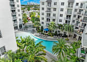 Thumbnail 15 of 40 - A pool surrounded by palm trees and apartment buildings.