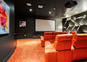 Thumbnail 11 of 40 - A room with orange seats and a large screen on the wall.