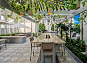 Thumbnail 4 of 40 - A patio with a table and chairs under a canopy of leaves.