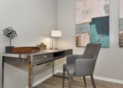 Thumbnail 21 of 32 - a desk with a chair and lamp in a room with paintings on the wall in The Oasis Daytona Apartment