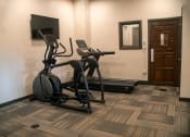 Thumbnail 7 of 12 - a gym with two treadmills and a tv in a hotel room