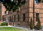 Thumbnail 1 of 12 - a brick building with a tree in front of it