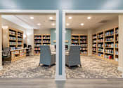 Thumbnail 5 of 26 - A library with two chairs in the middle of the room.