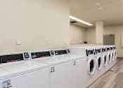 Thumbnail 9 of 26 - A row of white front load washing machines in a laundromat.