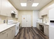 Thumbnail 10 of 26 - A kitchen with white appliances and wood floors.