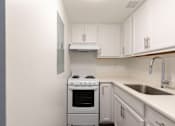 Thumbnail 12 of 26 - A white kitchen with a stove and sink.