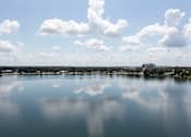Thumbnail 22 of 26 - A serene lake with a clear reflection of the sky and clouds.