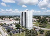 Thumbnail 1 of 26 - A tall white building with a parking lot in front of it.
