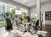 Thumbnail 5 of 40 - A gym with a variety of equipment including treadmills, stationary bikes, and elliptical machines.