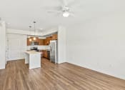 Thumbnail 21 of 57 - an empty living room with a kitchen and a ceiling fan