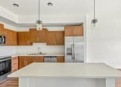 Thumbnail 28 of 57 - a kitchen with a large island and a stainless steel refrigerator