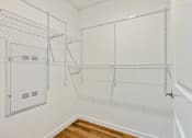 Thumbnail 46 of 57 - the walk in closet of a bedroom with white walls and shelves and a glass door