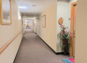 Thumbnail 10 of 24 - a residential corridor with flowers on the side of an apartment door