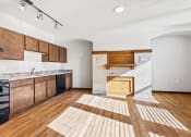 Thumbnail 1 of 12 - a spacious kitchen with wood cabinets and floors and black appliances at Horicon School Apartments