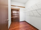 Thumbnail 4 of 12 - a walk-in closet with built-in shelving and wood flooring