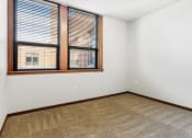 Thumbnail 5 of 12 - a bedroom with plush carpeting and a large window at Horicon School Apartments