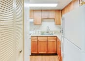 Thumbnail 8 of 18 - kitchen with white appliances, wood cabinets, and pantry doors