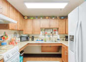 Thumbnail 7 of 18 - kitchen with oven/stove, fridge, wood cabinets, and overhead lighting