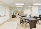 Thumbnail 2 of 18 - large community room with tables and chairs by computer station & library