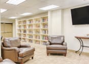 Thumbnail 4 of 18 - library with leather reading chairs, shelves of books, and TV