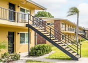 Thumbnail 34 of 37 - a yellow apartment building with stairs and a palm tree