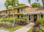 Thumbnail 11 of 37 - a yellow building with a leasing office and palm trees