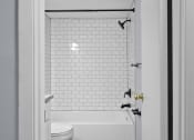 Thumbnail 29 of 37 - a bathroom with white subway tile and a tub and a toilet