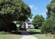 Thumbnail 9 of 18 - pathway surrounded by trees leading to residential buildings at Stillwater at Grandview Cove