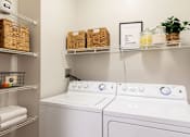 Thumbnail 27 of 40 - a white washer and dryer in a laundry room with baskets on shelves above