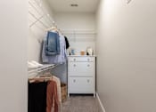 Thumbnail 22 of 40 - a walk in closet with clothes hanging on the wall and a dresser in it